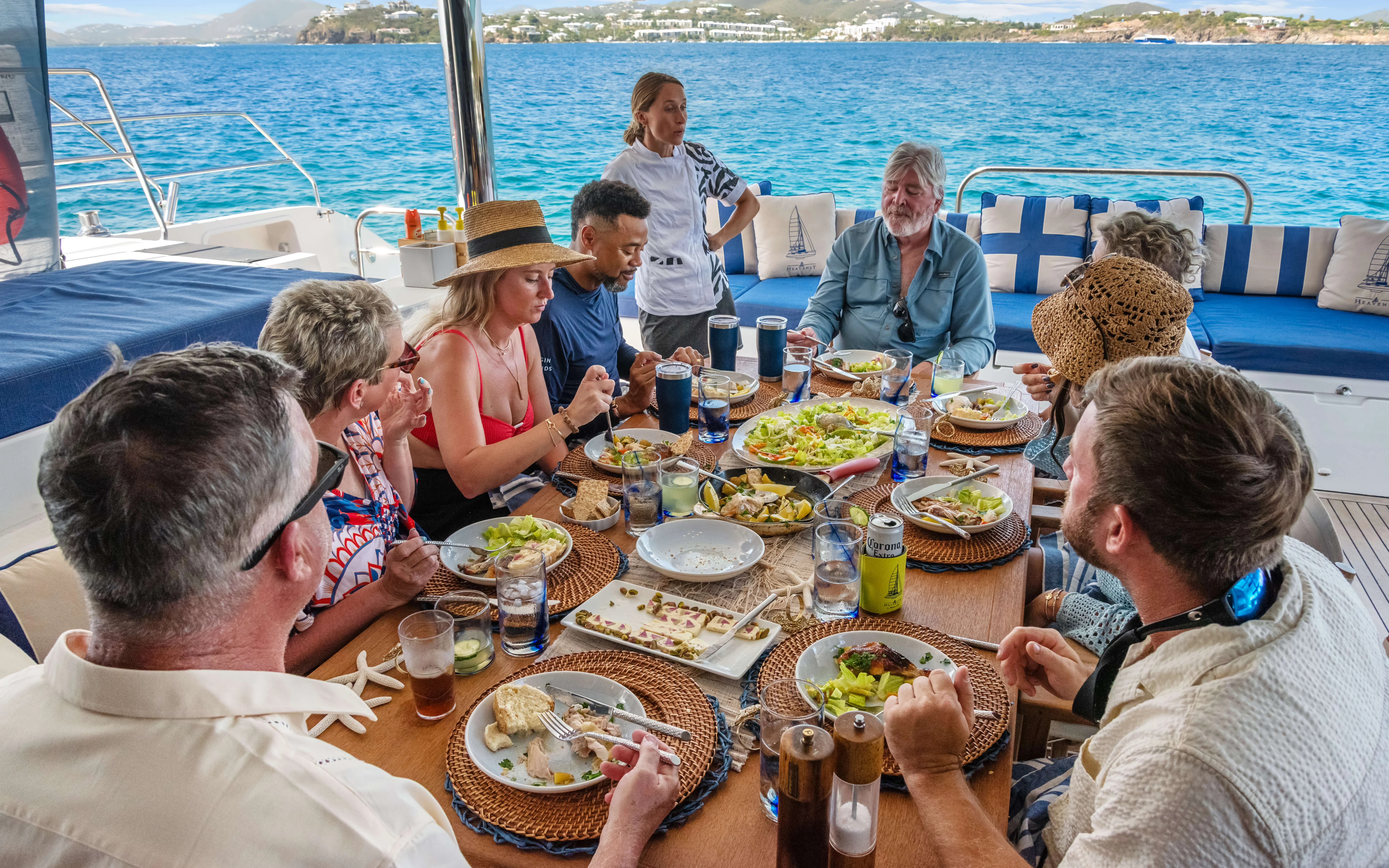 Group of guests sharing lunch on a yacht while the chef talks with them